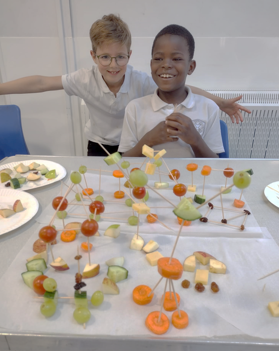Two children show off their amazing fruit constructions