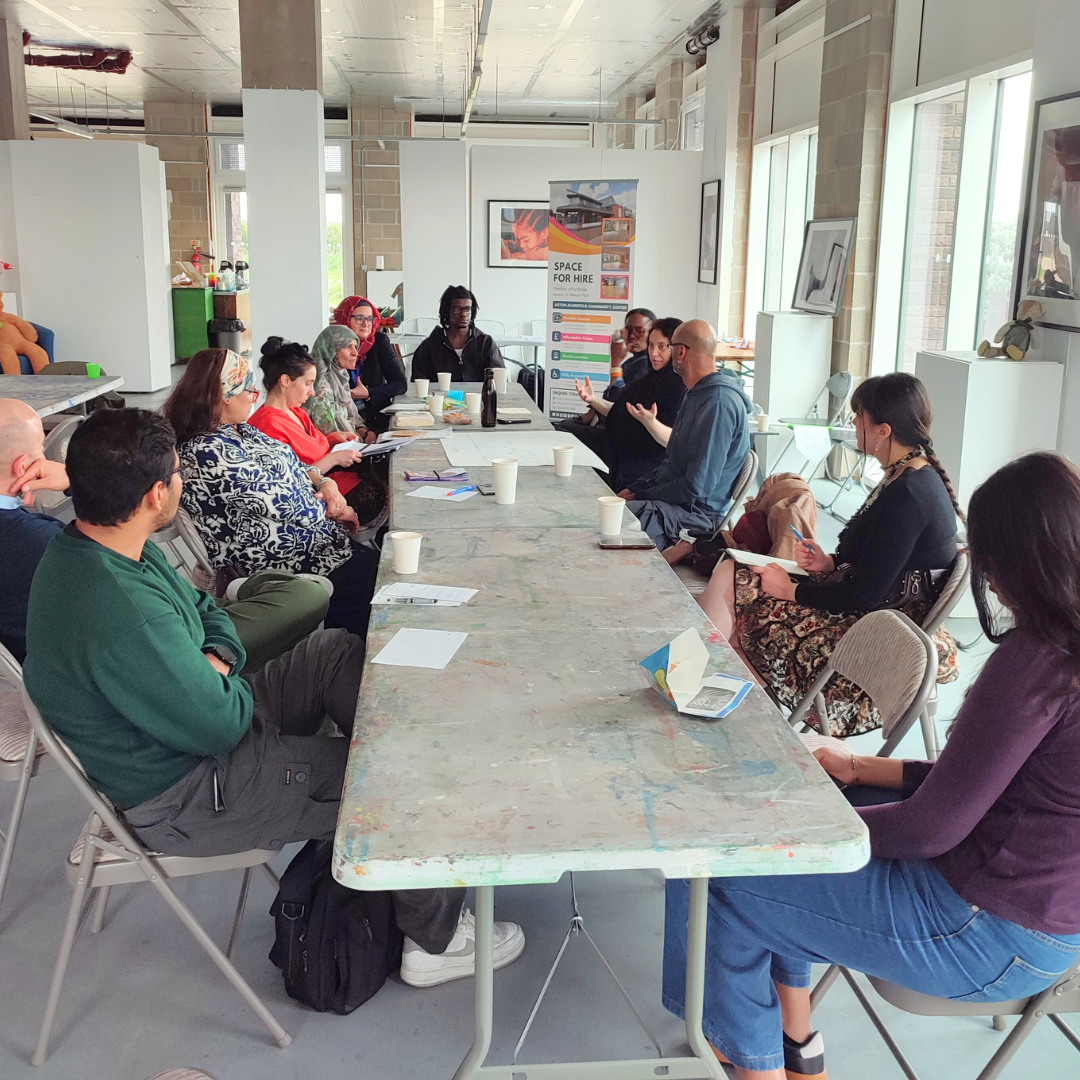 A diverse group of people sit at a long table at the networking event